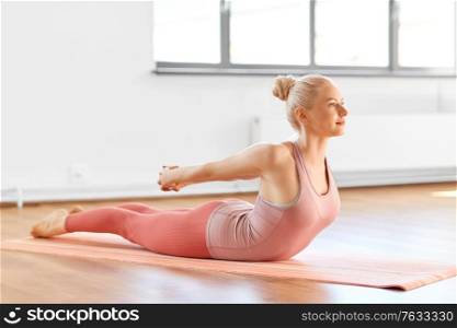 fitness, sport and healthy lifestyle concept - happy young woman doing yoga and bending her back on mat at home. young woman doing yoga bending her back at home