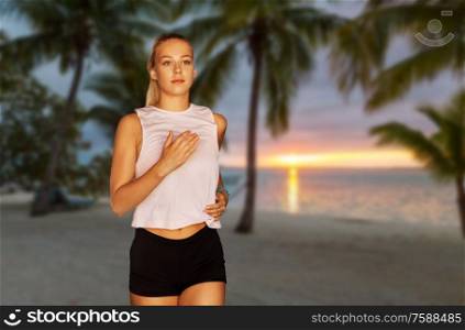 fitness, sport and healthy lifestyle concept - happy young woman running over tropical beach on background. happy young woman running along tropical beach
