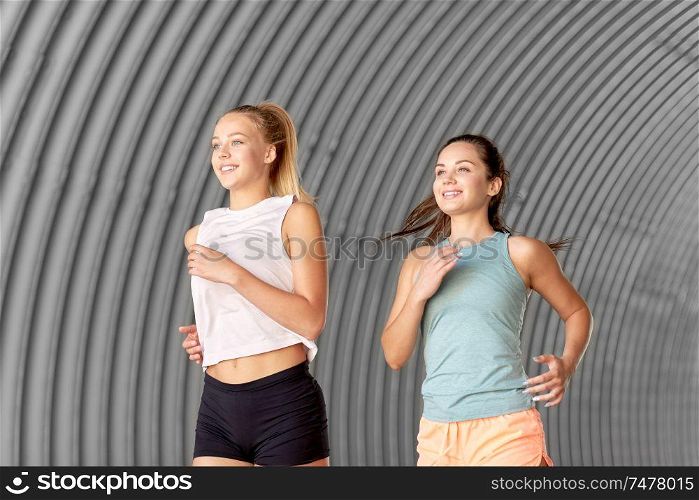 fitness, sport and healthy lifestyle concept - happy young women or female friends running outdoors. young women or female friends running outdoors