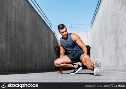 fitness, sport and healthy lifestyle concept - man exercising and stretching leg outdoors. man doing sports and stretching leg outdoors