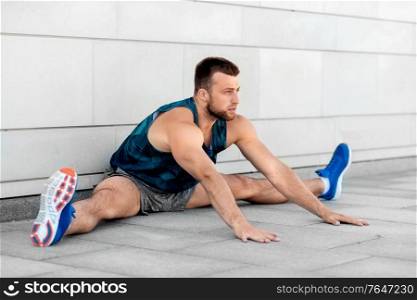fitness, sport and healthy lifestyle concept - man exercising and stretching outdoors. man doing sports and stretching outdoors