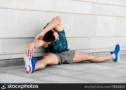 fitness, sport and healthy lifestyle concept - man exercising and stretching outdoors. man doing sports and stretching outdoors