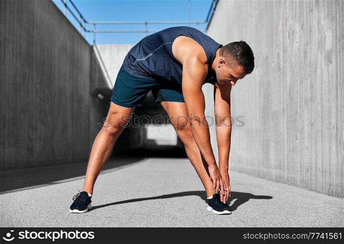 fitness, sport and healthy lifestyle concept - man exercising and stretching outdoors. man doing sports and stretching outdoors