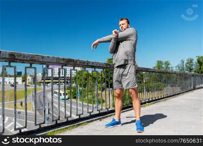 fitness, sport and healthy lifestyle concept - man stretching hand and shoulder on bridge. man stretching hand and shoulder on bridge