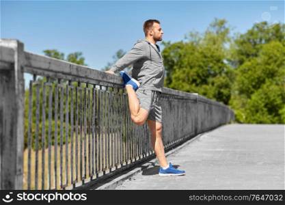 fitness, sport and healthy lifestyle concept - man stretching leg on bridge. man stretching leg on bridge