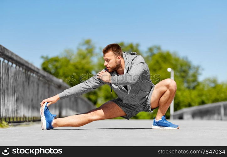 fitness, sport and healthy lifestyle concept - man stretching leg on bridge. man stretching leg on bridge