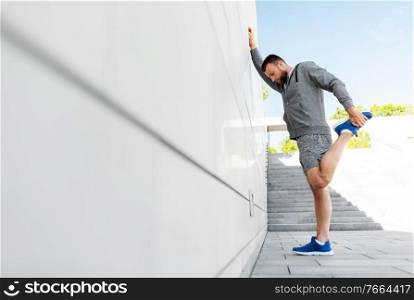 fitness, sport and healthy lifestyle concept - man stretching leg outdoors. man stretching leg outdoors