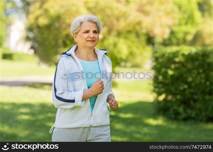 fitness, sport and healthy lifestyle concept - senior woman running along summer park. senior woman running along summer park