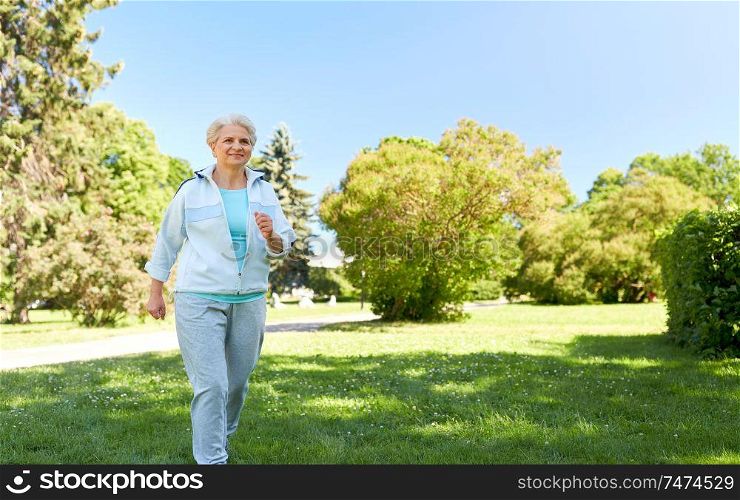 fitness, sport and healthy lifestyle concept - senior woman running or walking along summer park. senior woman running along summer park