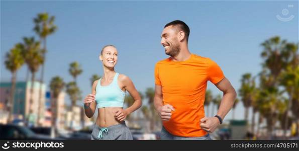 fitness, sport and healthy lifestyle concept - smiling couple jogging at summer over venice beach background in california. smiling couple jogging at summer over venice beach. smiling couple jogging at summer over venice beach