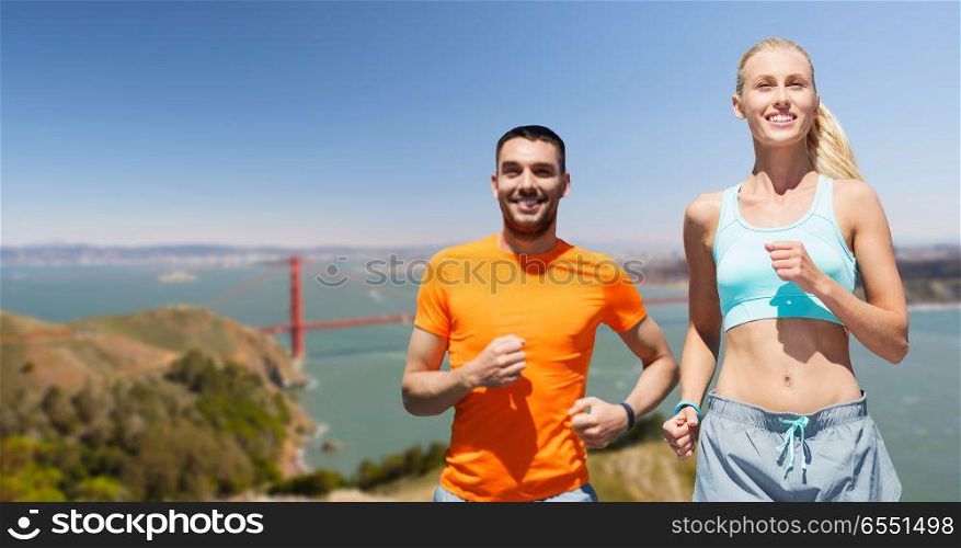fitness, sport and healthy lifestyle concept - smiling couple running over golden gate bridge in san francisco bay background. couple running over golden gate bridge background. couple running over golden gate bridge background