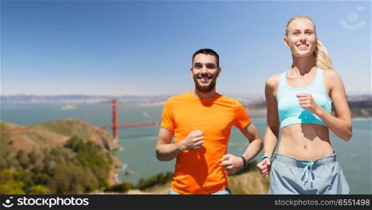 fitness, sport and healthy lifestyle concept - smiling couple running over golden gate bridge in san francisco bay background. couple running over golden gate bridge background. couple running over golden gate bridge background