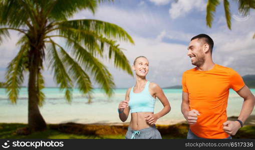 fitness, sport and healthy lifestyle concept - smiling couple running over tropical beach background in french polynesia. smiling couple running at summer seaside. smiling couple running at summer seaside