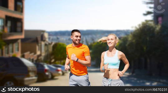 fitness, sport and healthy lifestyle concept - smiling couple with heart-rate watch running over san francisco city background. smiling couple running. smiling couple running