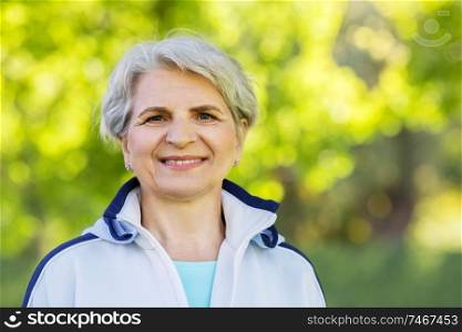 fitness, sport and healthy lifestyle concept - smiling sporty senior woman at summer park. smiling sporty senior woman at summer park