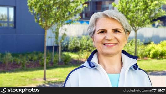 fitness, sport and healthy lifestyle concept - smiling sporty senior woman over city street background. smiling sporty senior woman in city