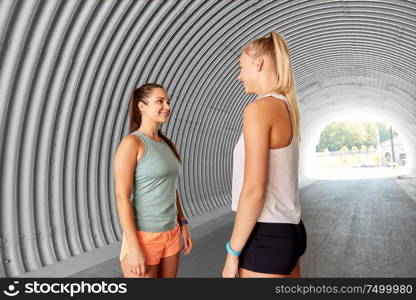 fitness, sport and healthy lifestyle concept - smiling sporty young women or female friends in tunnel. sporty young women or female friends in tunnel