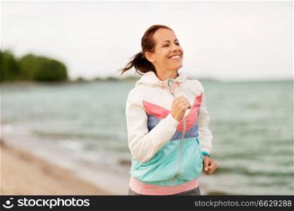 fitness, sport and healthy lifestyle concept - smiling woman running along beach. smiling woman running along beach