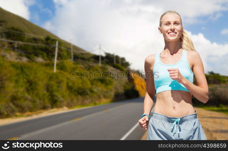 fitness, sport and healthy lifestyle concept - smiling woman running nearby road over big sur hills and road background in california. happy woman running nearby road over big sur hills. happy woman running nearby road over big sur hills