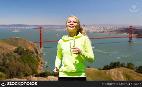 fitness, sport and healthy lifestyle concept - smiling woman running over golden gate bridge in san francisco bay background. smiling woman running over golden gate bringe. smiling woman running over golden gate bringe