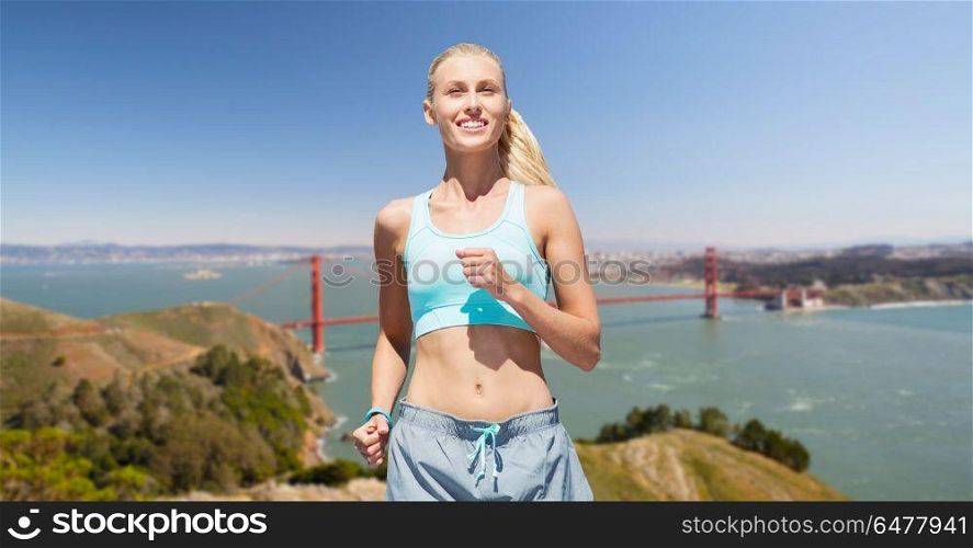fitness, sport and healthy lifestyle concept - smiling woman running over golden gate bridge in san francisco bay background. woman running over golden gate bridge background. woman running over golden gate bridge background