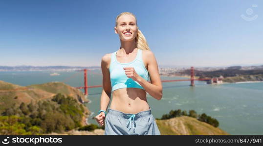 fitness, sport and healthy lifestyle concept - smiling woman running over golden gate bridge in san francisco bay background. woman running over golden gate bridge background. woman running over golden gate bridge background