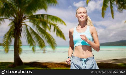 fitness, sport and healthy lifestyle concept - smiling woman running over tropical beach background in french polynesia. smiling woman running at summer. smiling woman running at summer