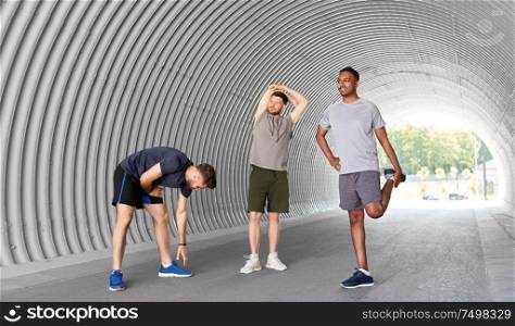 fitness, sport and healthy lifestyle concept - smiling young men or male friends stretching before training outdoors. men or male friends stretching before training
