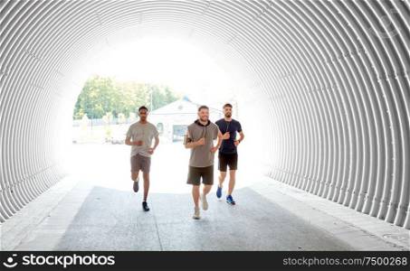 fitness, sport and healthy lifestyle concept - smiling young men or male friends with earphones running outdoors. male friends with earphones running outdoors