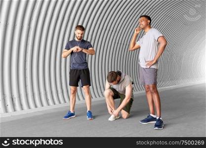 fitness, sport and healthy lifestyle concept - smiling young men or male friends with earphones training outdoors. male friends with earphones training outdoors