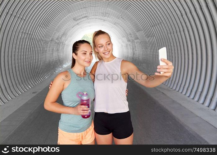 fitness, sport and healthy lifestyle concept - smiling young women or female friends taking selfie by smartphone outdoors. sporty women taking selfie by smartphone outdoors