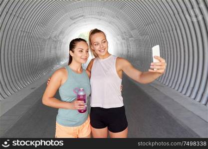 fitness, sport and healthy lifestyle concept - smiling young women or female friends taking selfie by smartphone outdoors. sporty women taking selfie by smartphone outdoors