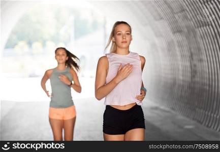fitness, sport and healthy lifestyle concept - smiling young women or female friends running outdoors. young women or female friends running outdoors