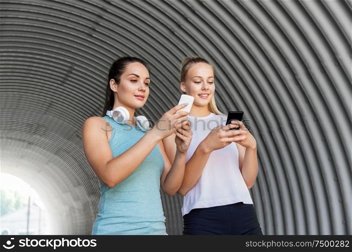 fitness, sport and healthy lifestyle concept - smiling young women or female friends with smartphones. women or female friends with smartphones