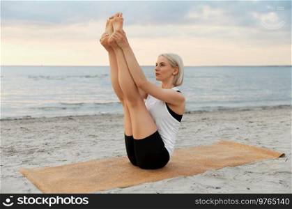 fitness, sport, and healthy lifestyle concept - woman doing yoga boat pose on beach over sunset. woman doing yoga boat pose on beach