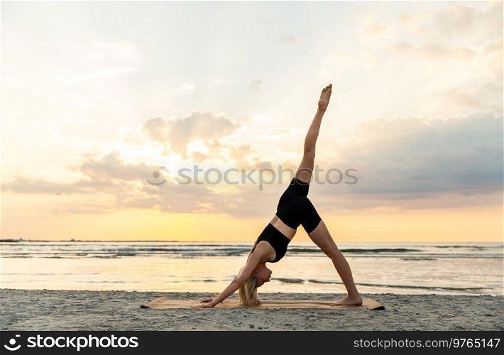 fitness, sport, and healthy lifestyle concept - woman doing yoga downward facing dog pose on beach over sunset. woman doing yoga downward facing dog pose on beach