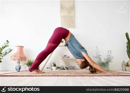 fitness, sport and healthy lifestyle concept - woman doing yoga downward-facing dog pose on mat at studio. woman does downward-facing dog pose at yoga studio