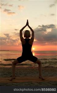 fitness, sport, and healthy lifestyle concept - woman doing yoga goddess pose on beach over sunset. woman doing yoga goddess pose on beach