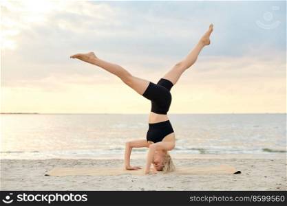 fitness, sport, and healthy lifestyle concept - woman doing yoga headstand on beach over sunset. woman doing yoga headstand on beach