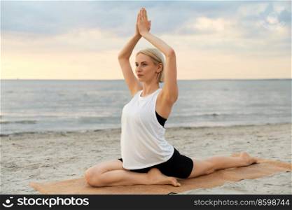 fitness, sport, and healthy lifestyle concept - woman doing yoga pigeon pose on beach over sunset. woman doing yoga pigeon pose on beach