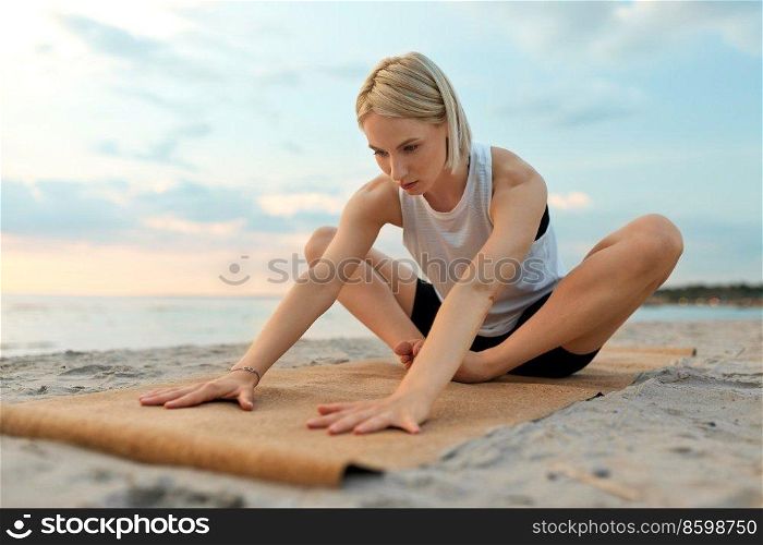 fitness, sport, and healthy lifestyle concept - woman doing yoga stretching pose on beach over sunset. woman doing yoga stretching pose on beach