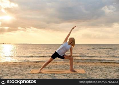 fitness, sport, and healthy lifestyle concept - woman doing yoga triangle pose on beach over sunset. woman doing yoga triangle pose on beach