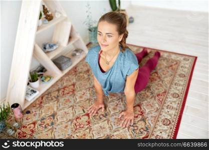 fitness, sport and healthy lifestyle concept - woman doing yoga upward-facing dog pose on mat at studio. woman doing upward-facing dog pose at yoga studio