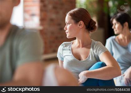 fitness, sport and healthy lifestyle concept - woman with group of people doing yoga seated spinal twist pose in gym or studio. woman with group of people doing yoga at studio. woman with group of people doing yoga at studio
