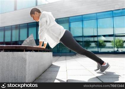 fitness, sport and healthy lifestyle concept - young african american woman doing bench push-ups at outdoors. african american woman doing sports outdoors
