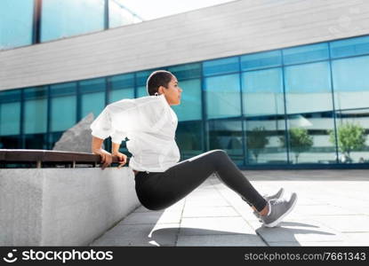 fitness, sport and healthy lifestyle concept - young african american woman doing bench triceps dip outdoors. african american woman doing sports outdoors