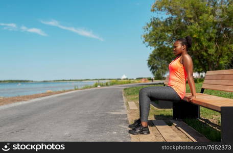 fitness, sport and healthy lifestyle concept - young african american woman exercising with bench at seaside. african american woman doing sports at seaside