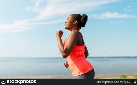 fitness, sport and healthy lifestyle concept - young african american woman running at seaside. young african american woman running at seaside