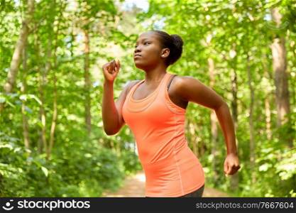 fitness, sport and healthy lifestyle concept - young african american woman running in forest. young african american woman running in forest