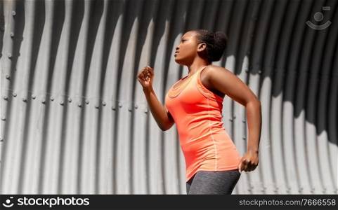 fitness, sport and healthy lifestyle concept - young african american woman running in tunnel. young african american woman running in tunnel